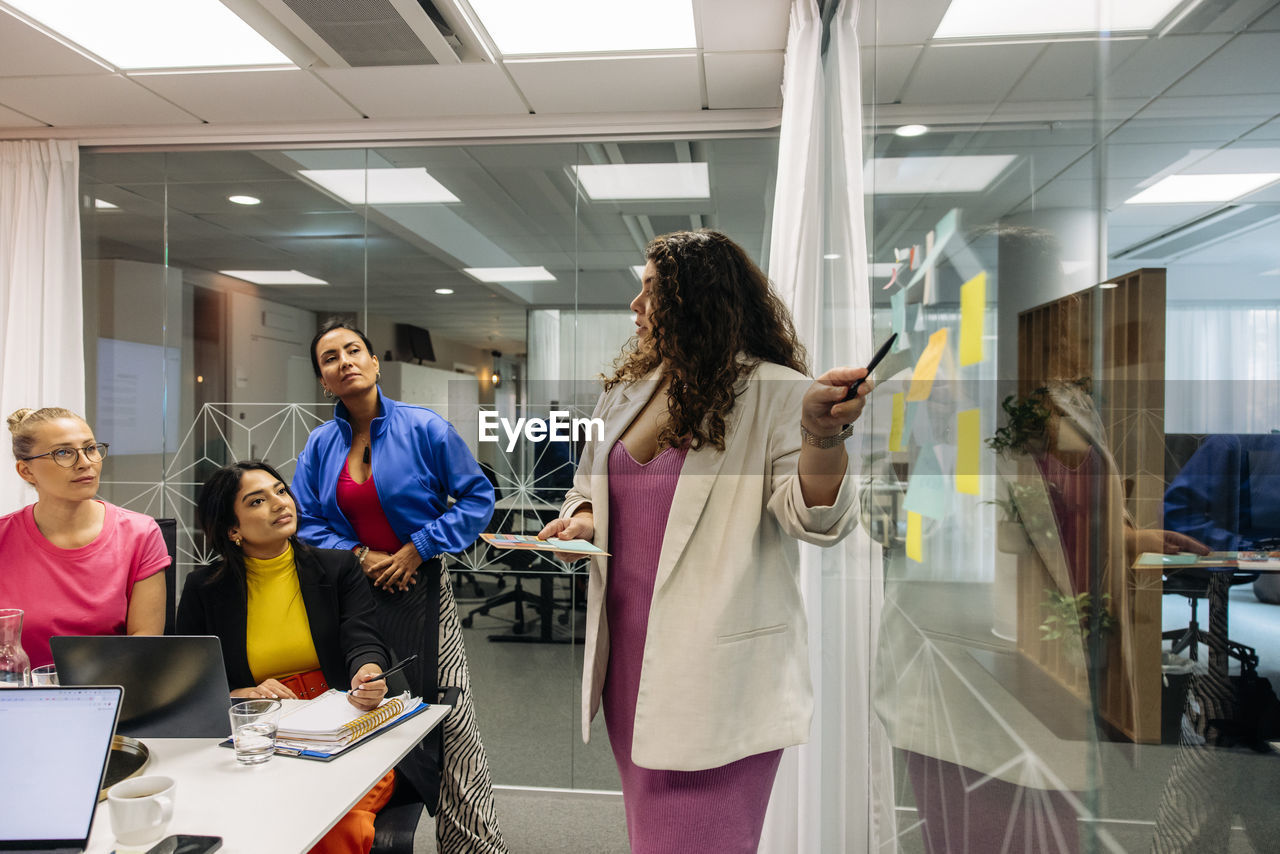 Female entrepreneur explaining colleagues while doing brainstorming session at office