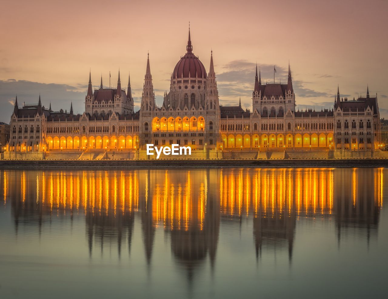 Illuminated hungarian parliament building by river at dusk
