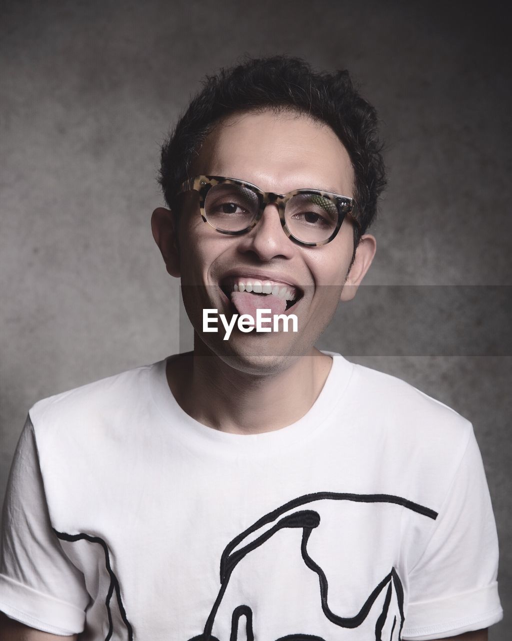 PORTRAIT OF SMILING YOUNG MAN WEARING EYEGLASSES