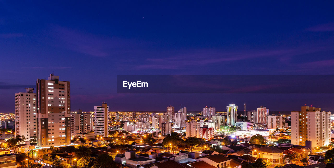 Illuminated buildings in city against sky at night