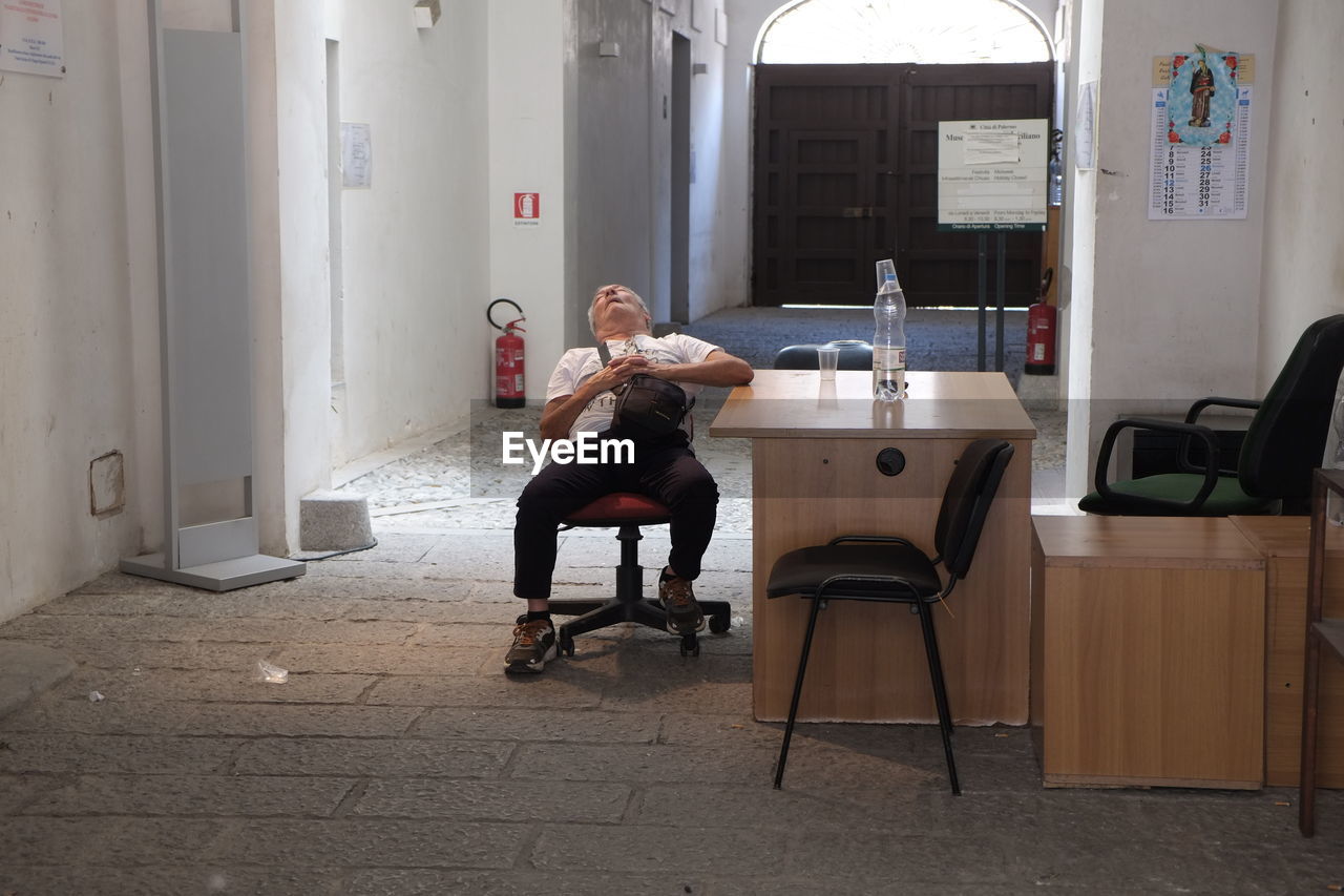 FULL LENGTH OF MAN SITTING ON CHAIR IN CAFE