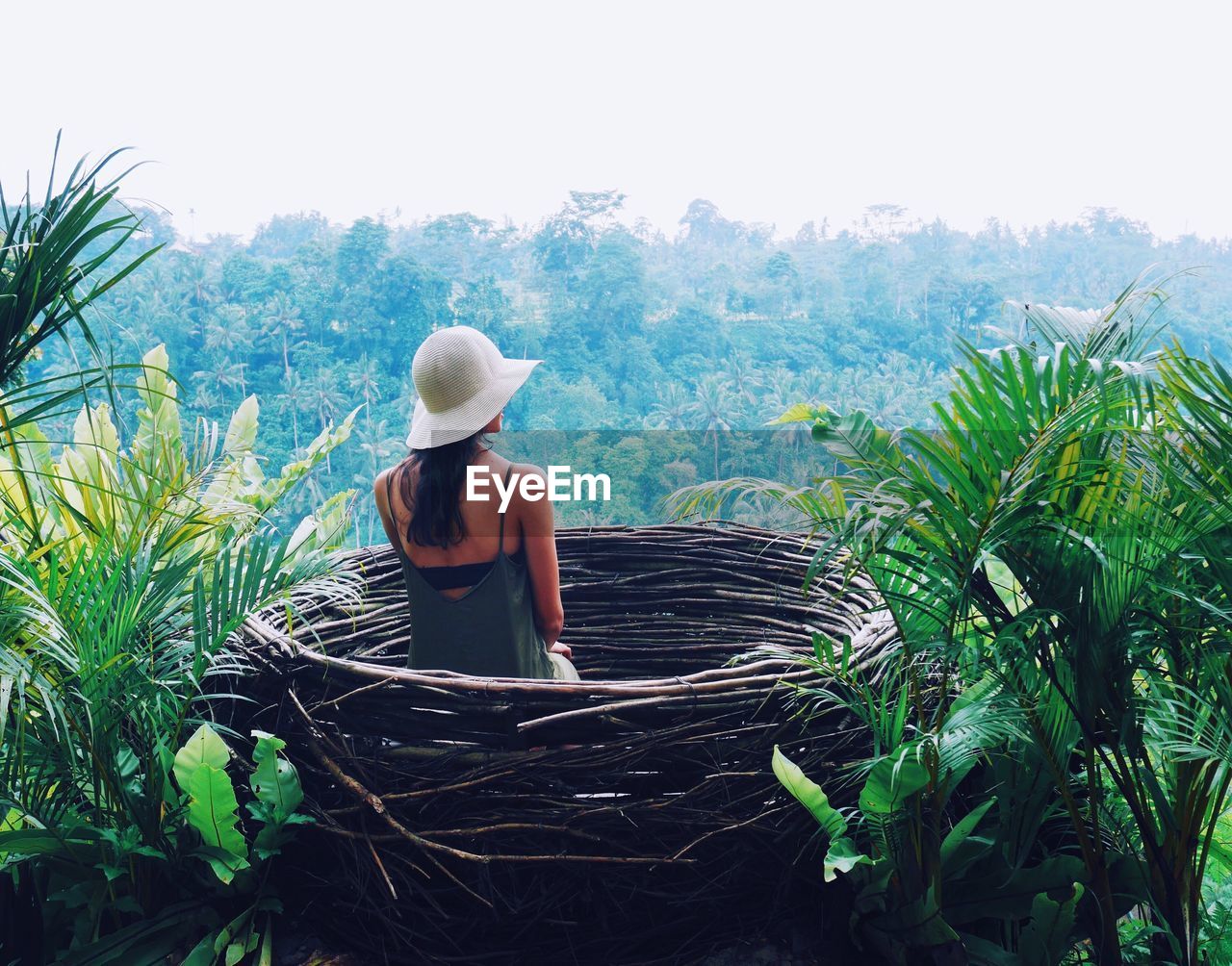Rear view of woman in artificial nest against trees