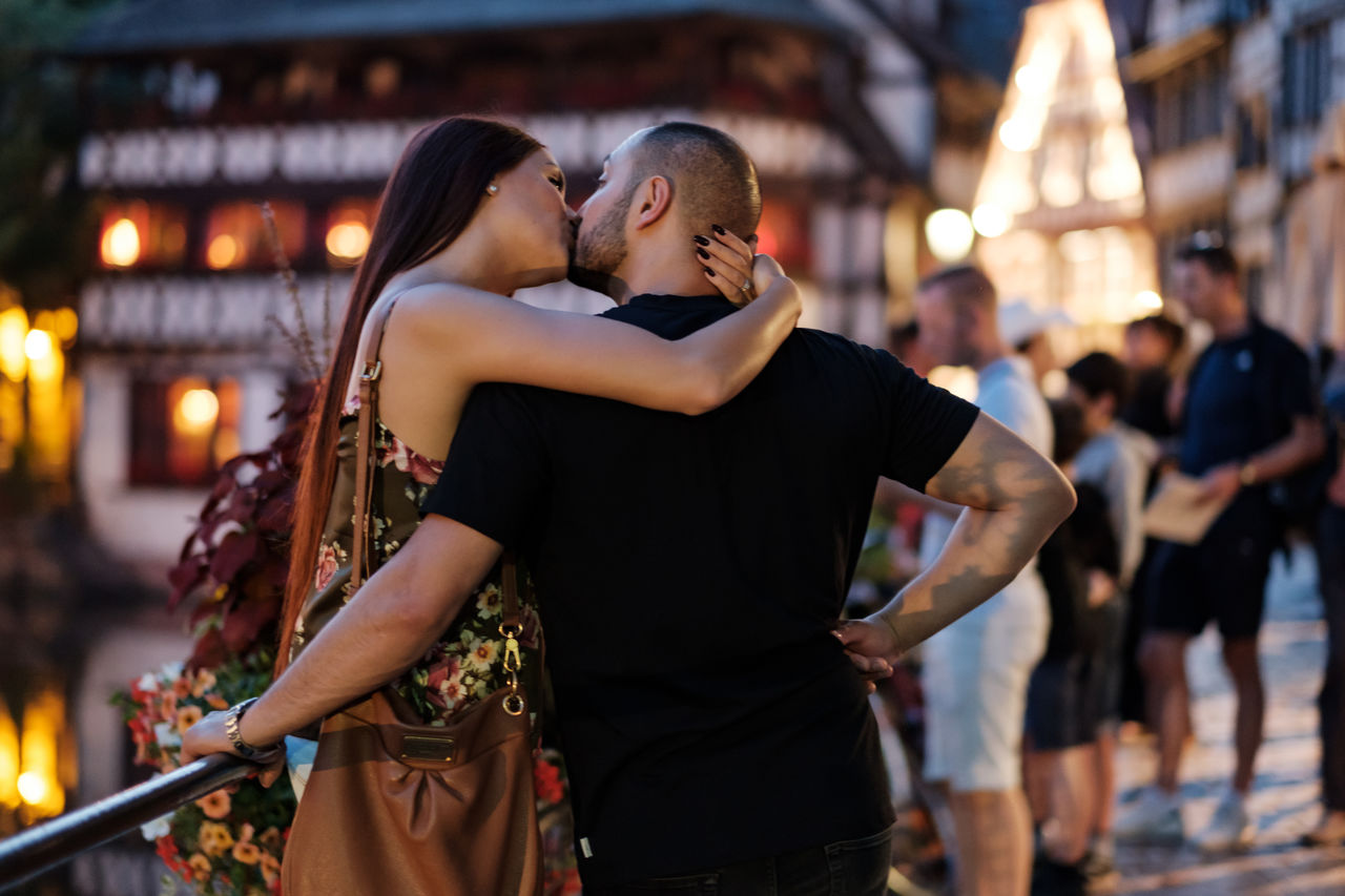 MIDSECTION OF COUPLE HOLDING HANDS AT CAMERA