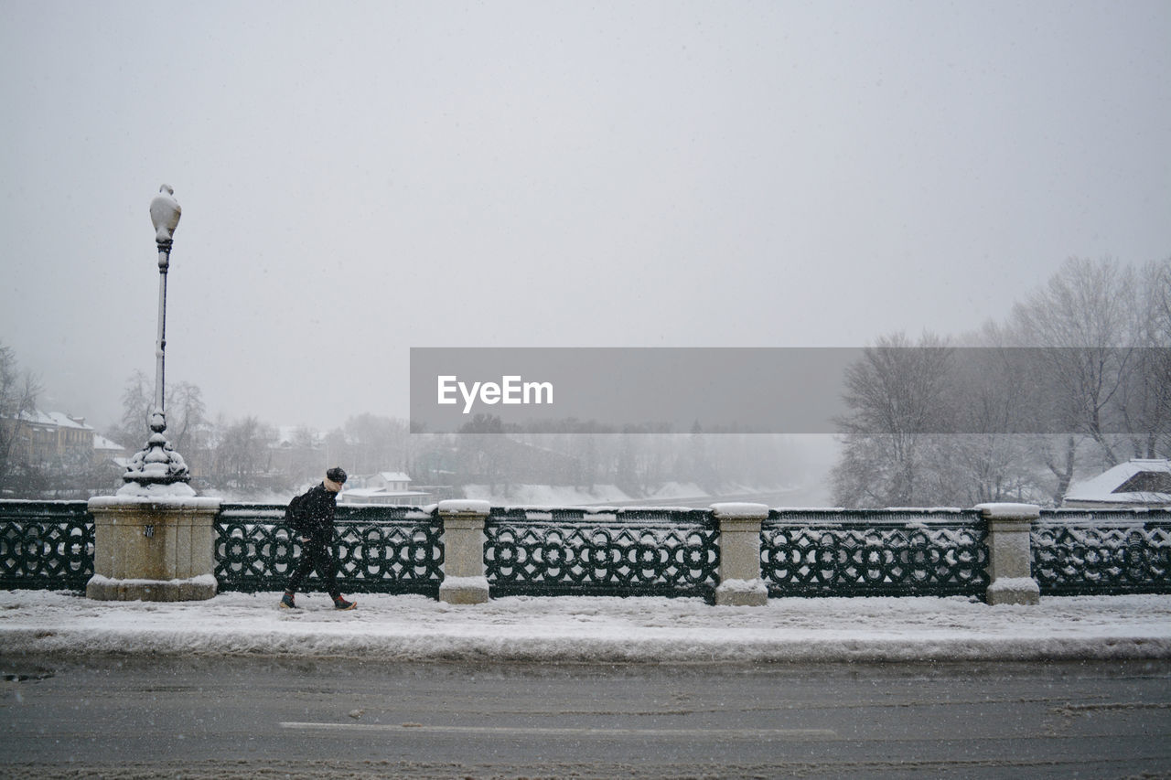 Man walking on sidewalk in city during winter