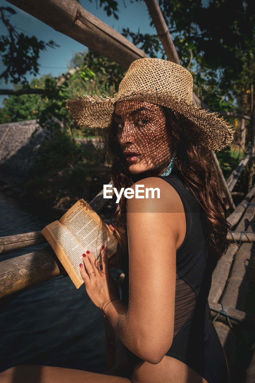 Midsection of woman holding book while sitting outdoors