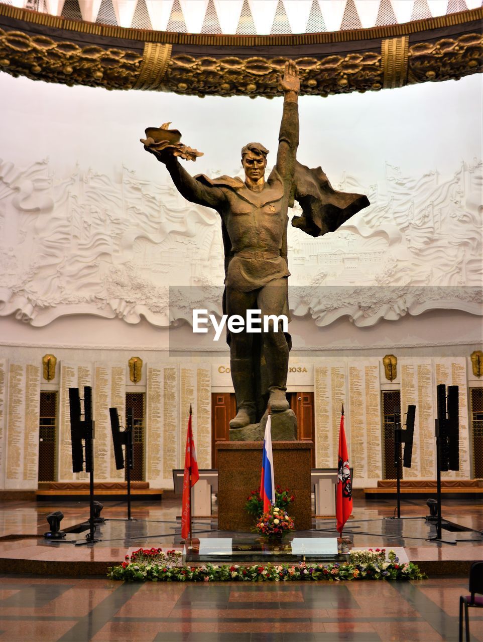 LOW ANGLE VIEW OF WOMAN STANDING BY STATUE AGAINST BUILDING