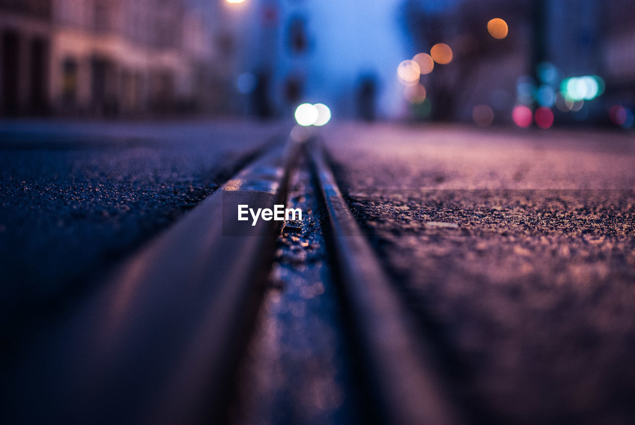 Close-up of railroad track on street in city at night