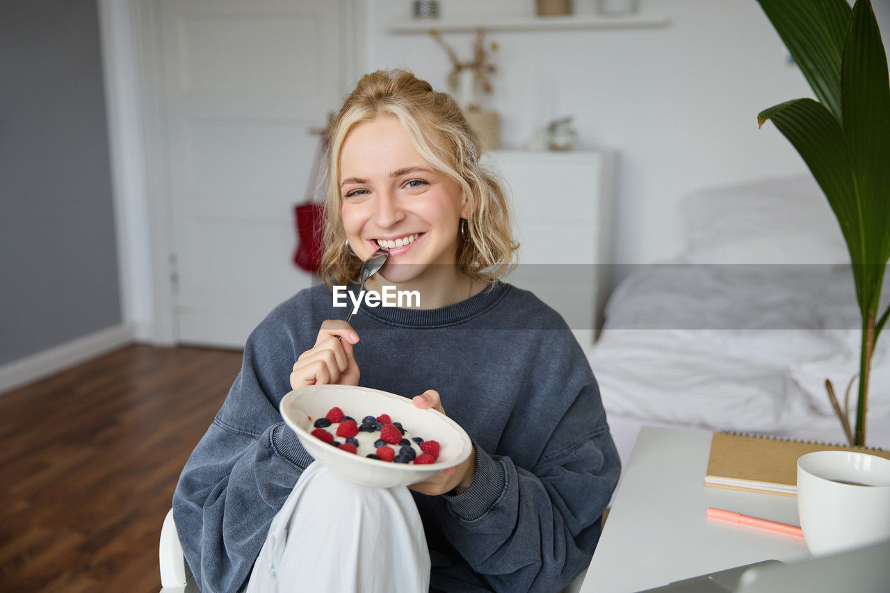 portrait of smiling young woman having breakfast at home