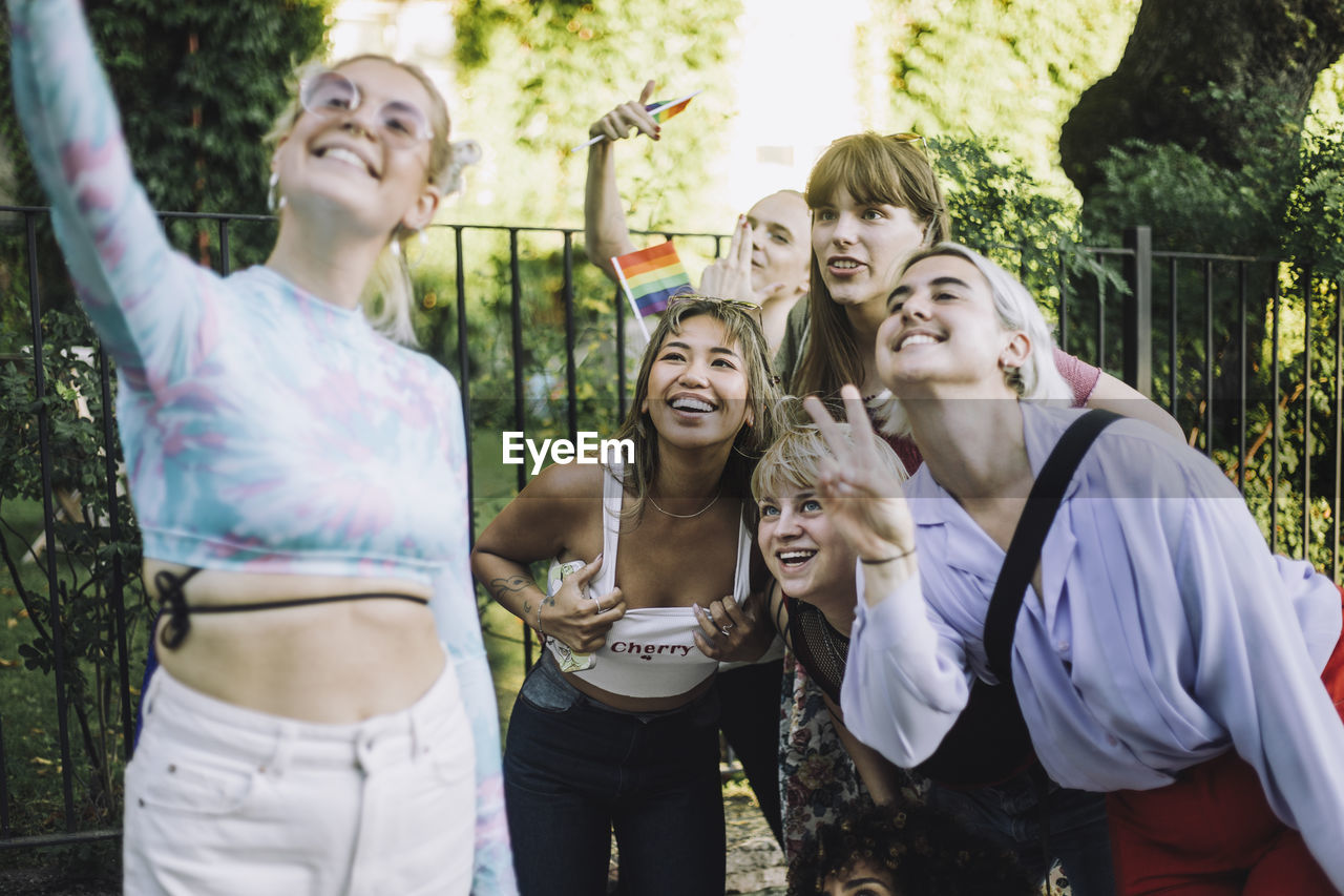 Happy woman taking selfie with friends gesturing and showing peace sign