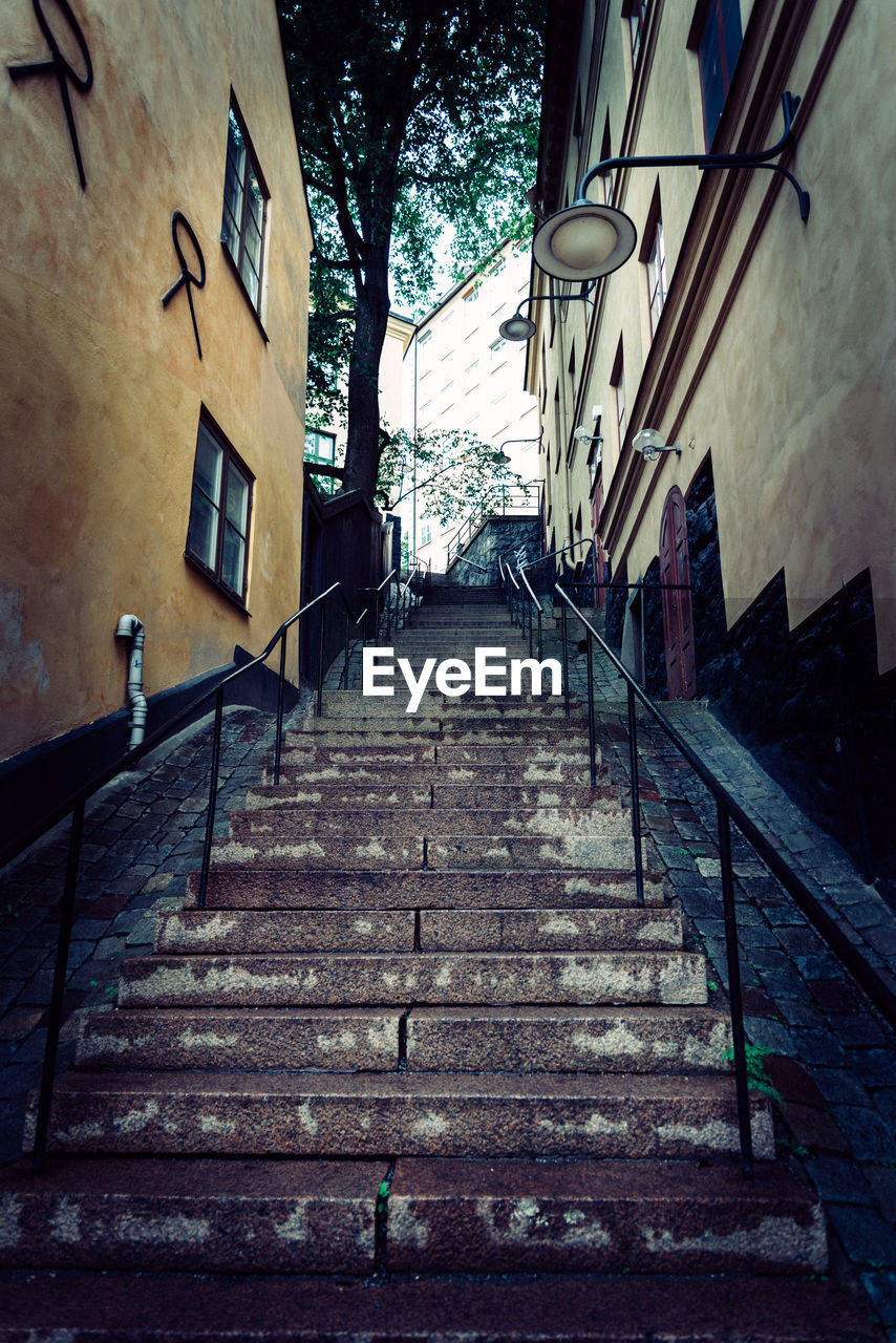 LOW ANGLE VIEW OF STAIRCASE AMIDST BUILDINGS