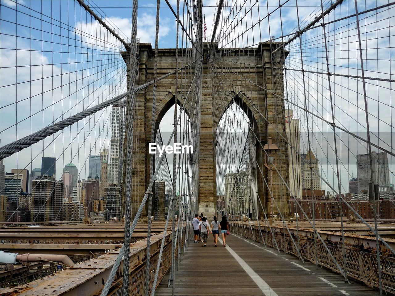 People walking on suspension bridge in city