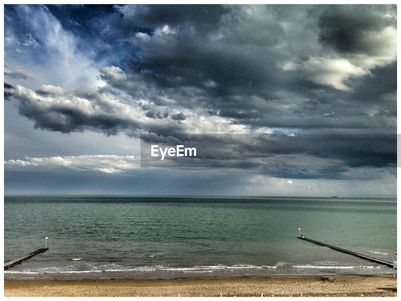 Scenic view of beach against cloudy sky