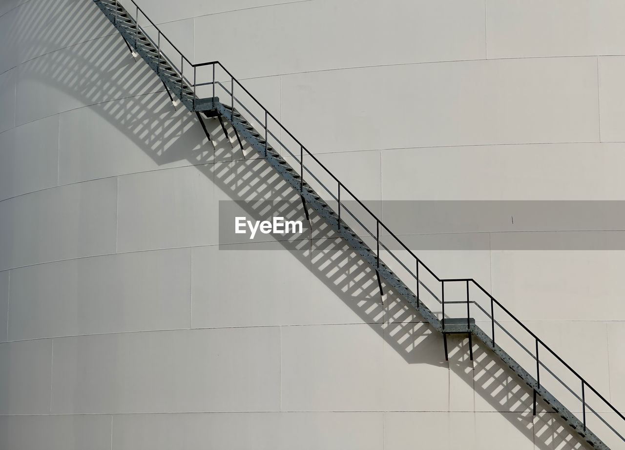 Low angle view of industrial staircase against gas silo 