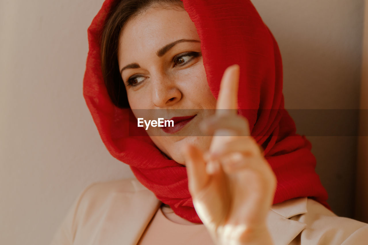 CLOSE-UP PORTRAIT OF BEAUTIFUL YOUNG WOMAN HOLDING RED