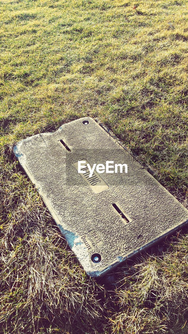 High angle view of text on manhole lid amidst grassy field at park