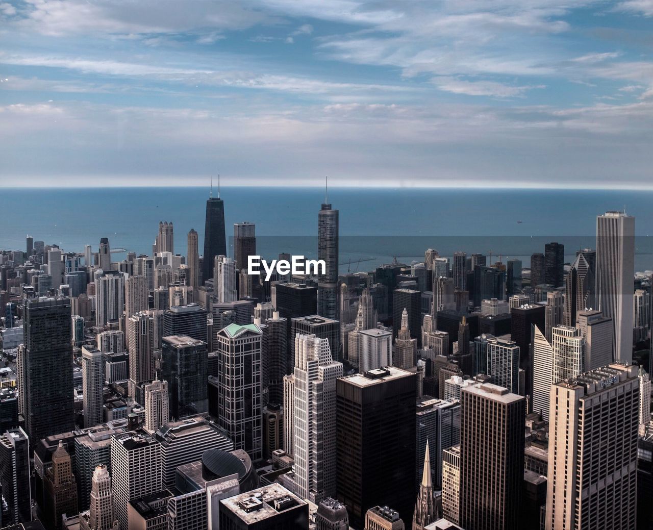 High angle view of cityscape by river against cloudy sky