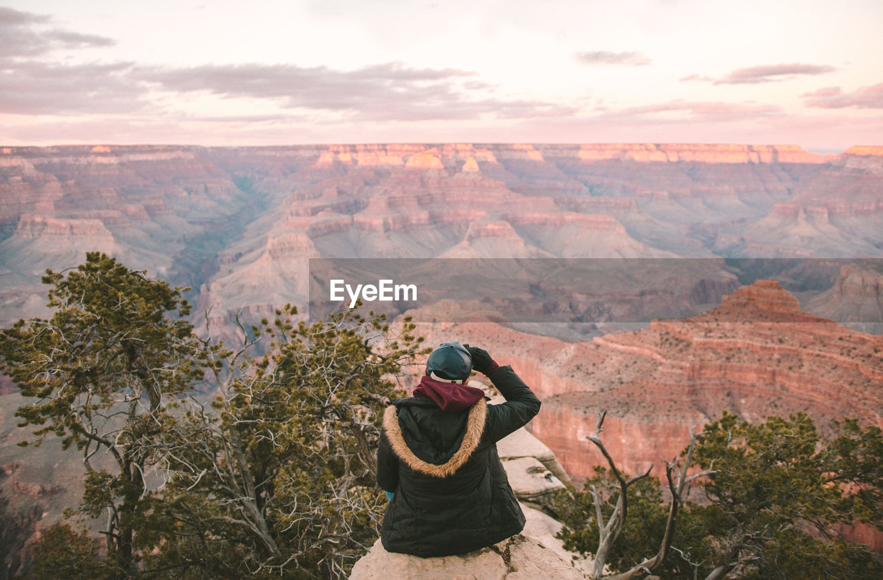 Rear view of person sitting on rock against grand canyon national park