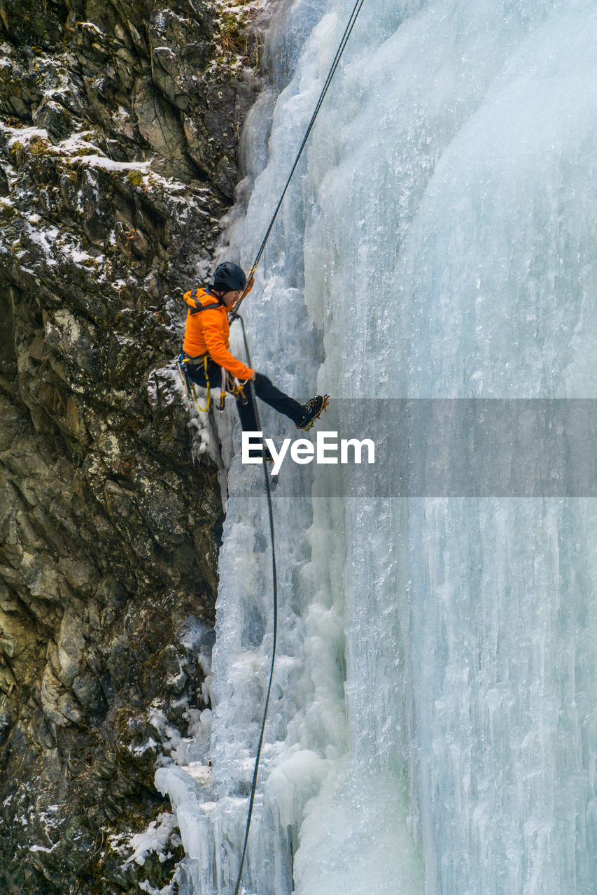 Side view of man climbing on snowcapped mountain