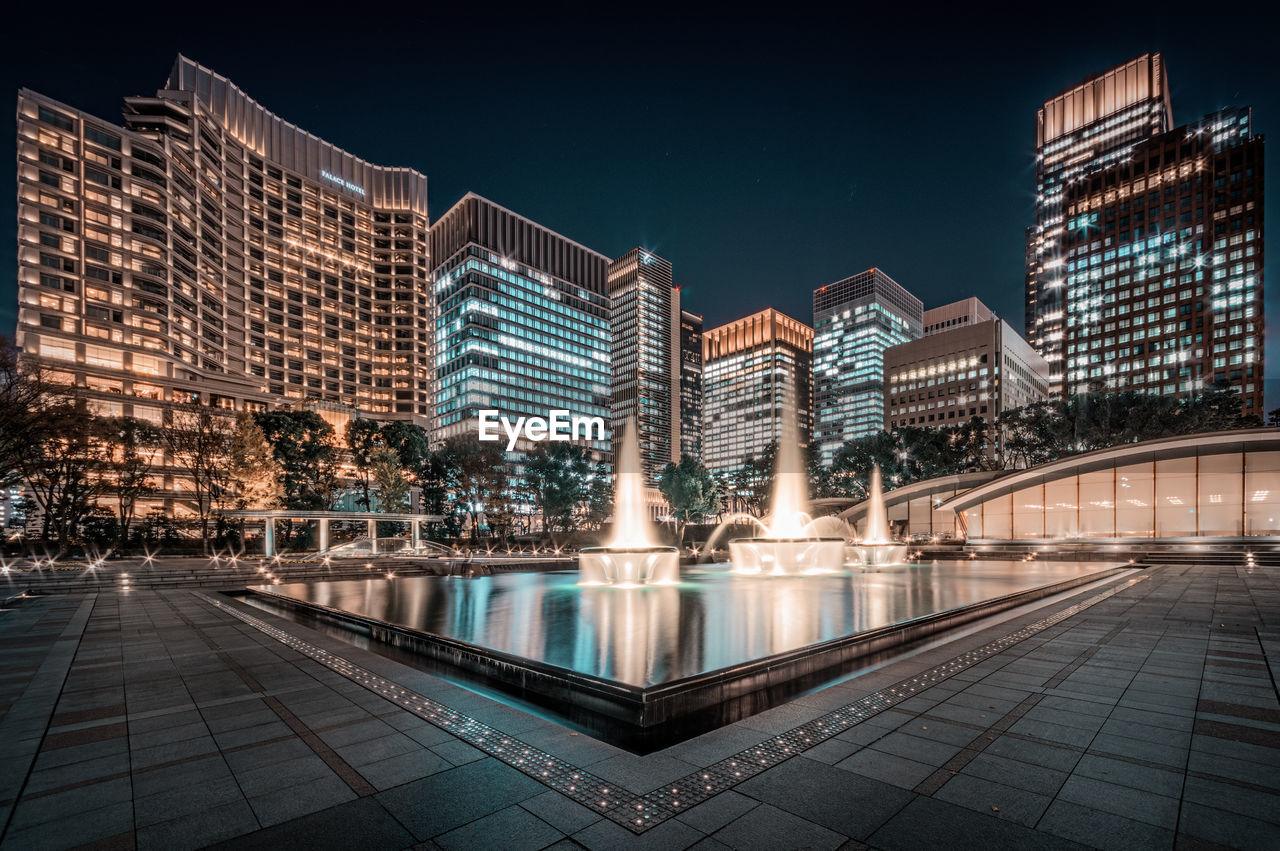 Blurred motion against illuminated modern buildings in city at night