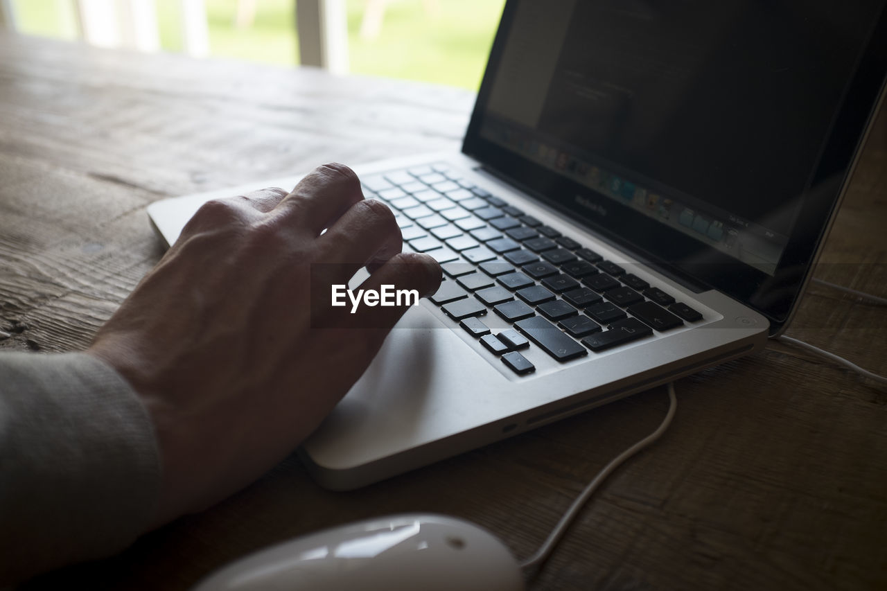 CROPPED IMAGE OF PERSON HOLDING LAPTOP