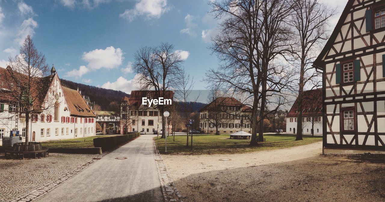 Empty road amidst buildings against sky on sunny day at blaubeuren