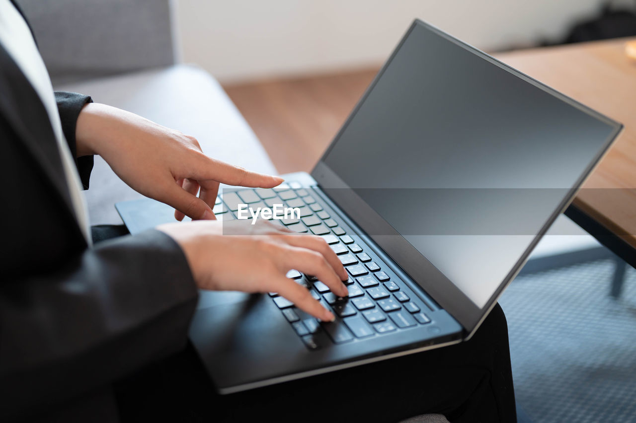 Midsection of woman using laptop on table