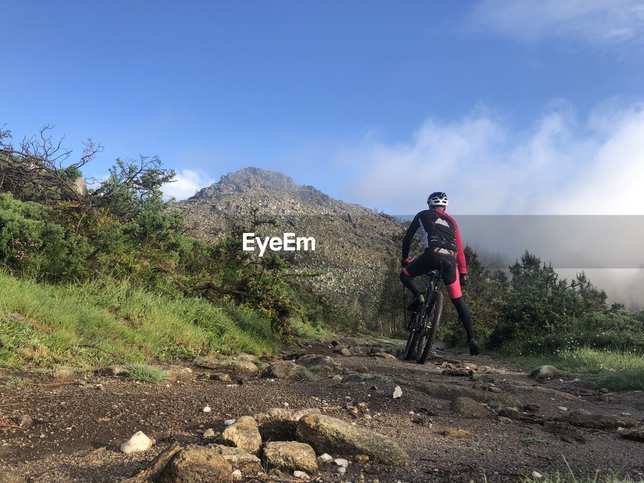 Man riding bicycle on mountain against sky