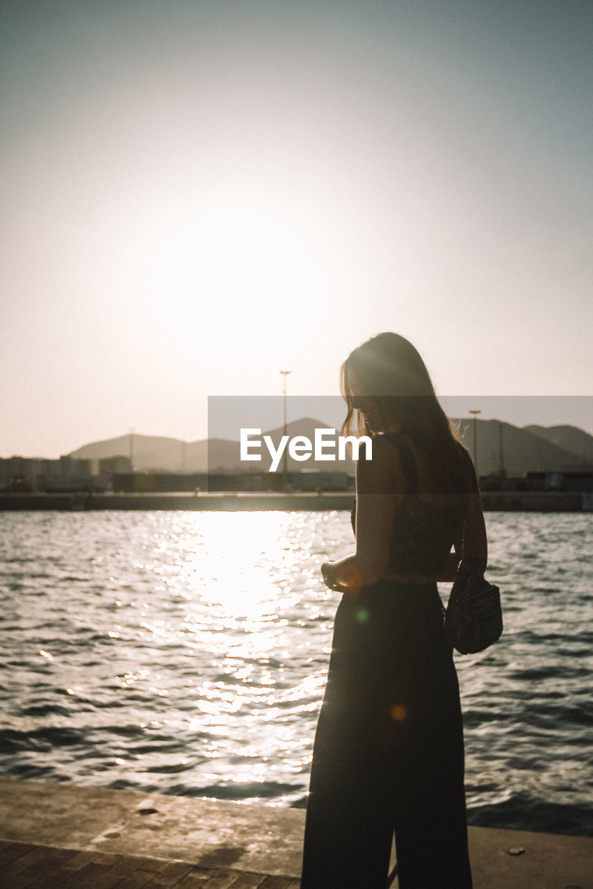 Woman standing by river against sky