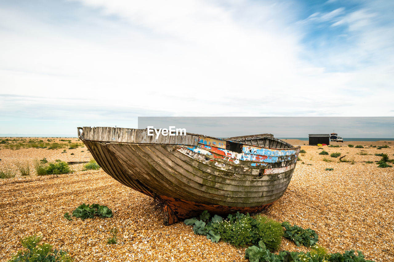 Abandoned boat moored on beach against sky