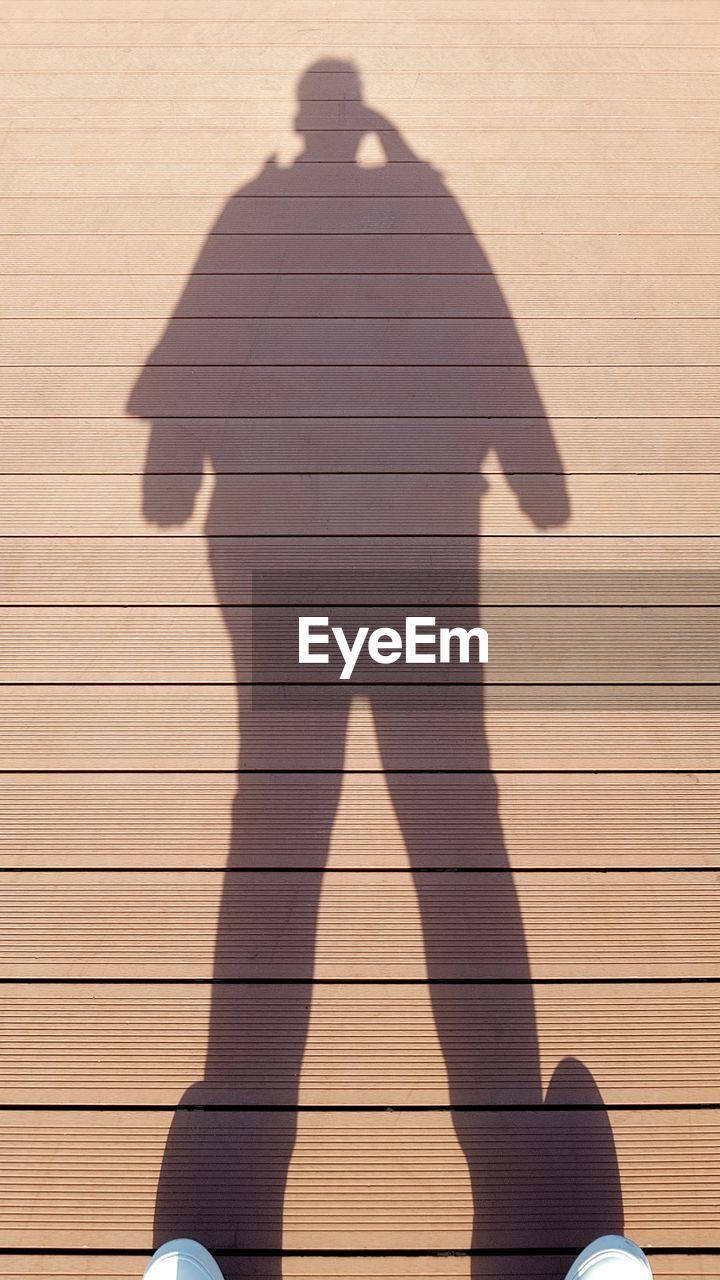 HIGH ANGLE VIEW OF SHADOW OF WOMAN ON TILED FLOOR