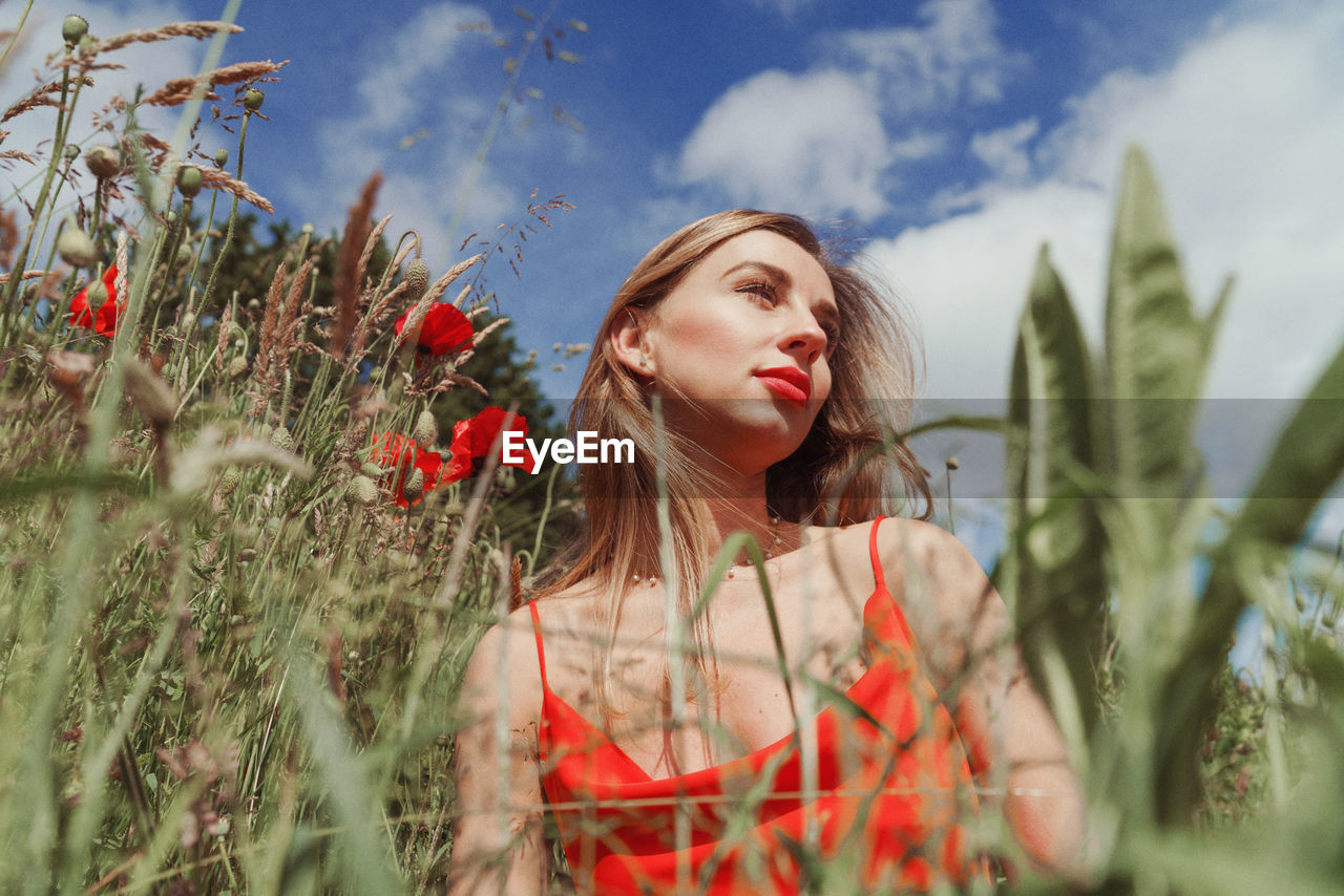 Portrait of young woman on field against sky