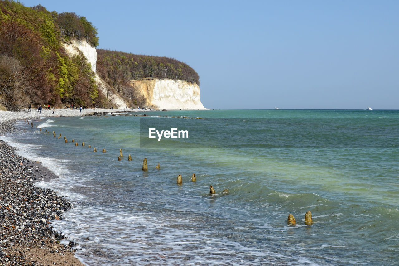 Scenic view of sea by chalk cliff against clear sky