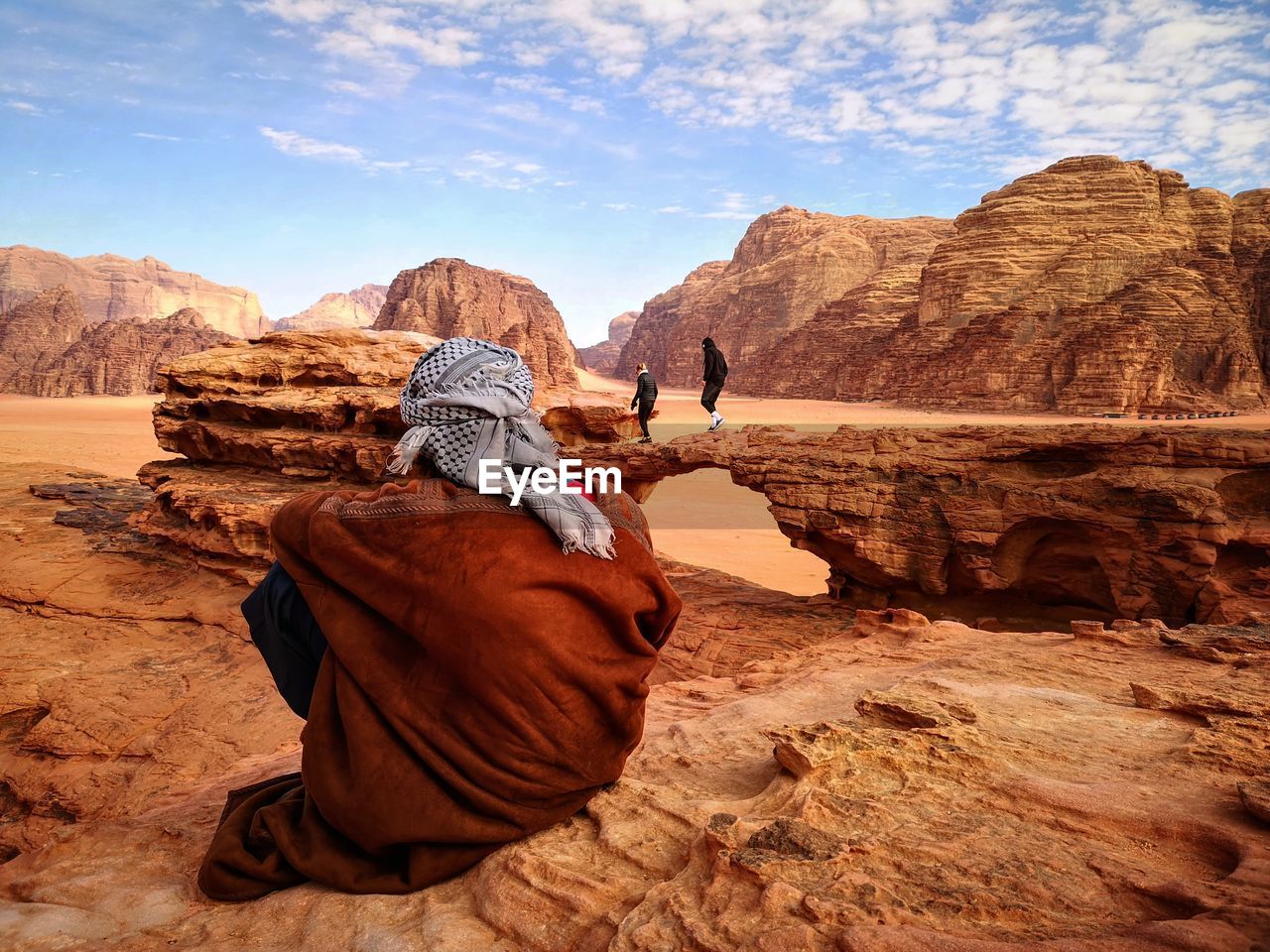 Rear view of man sitting on rock formation at desert
