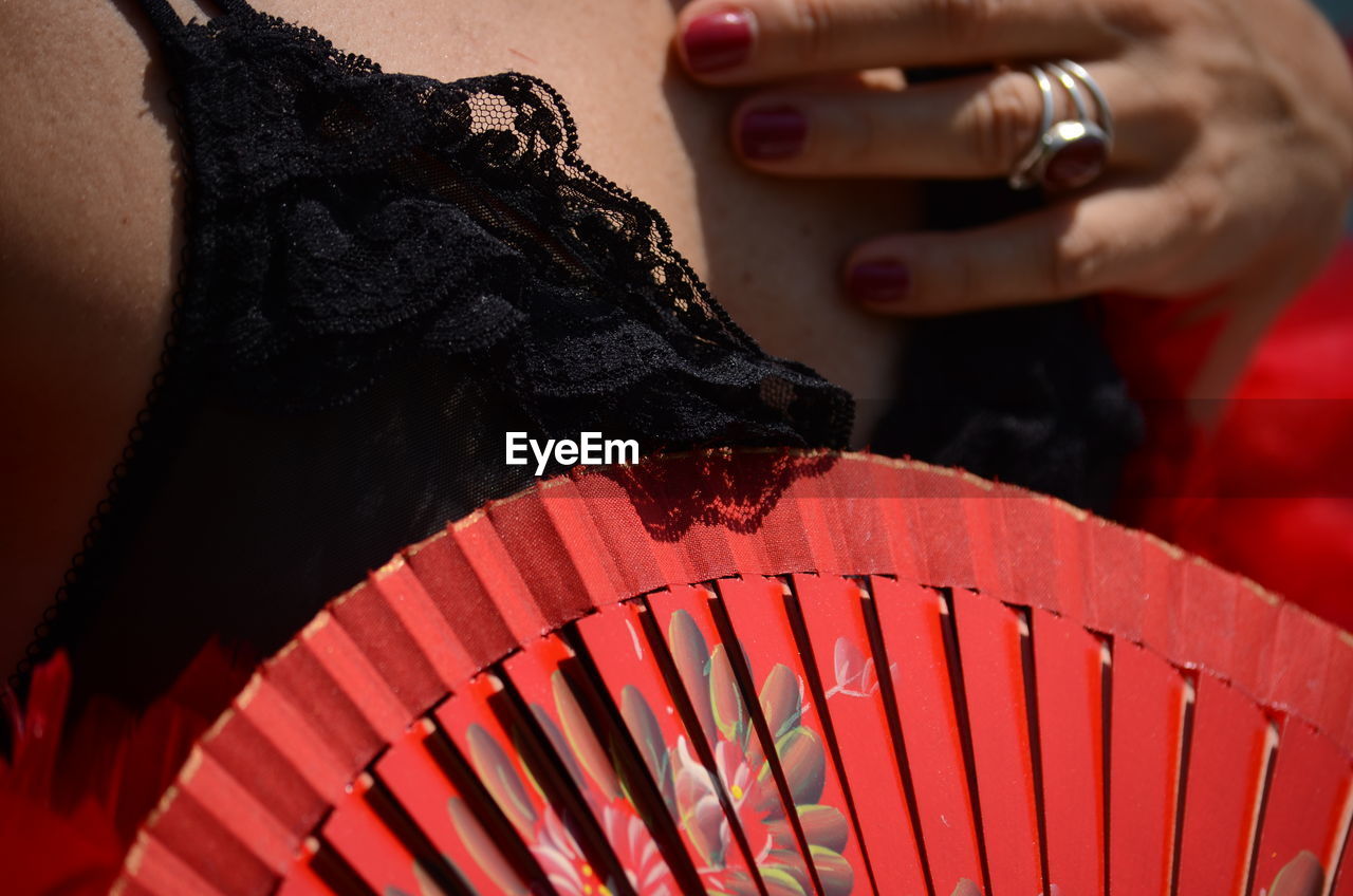Close-up midsection of woman holding hand fan