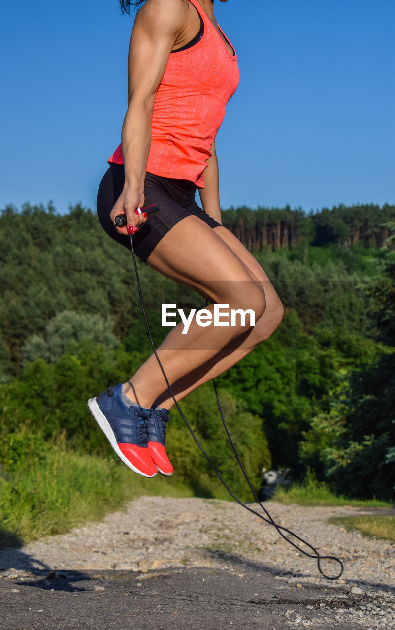 Low section of woman skipping on footpath