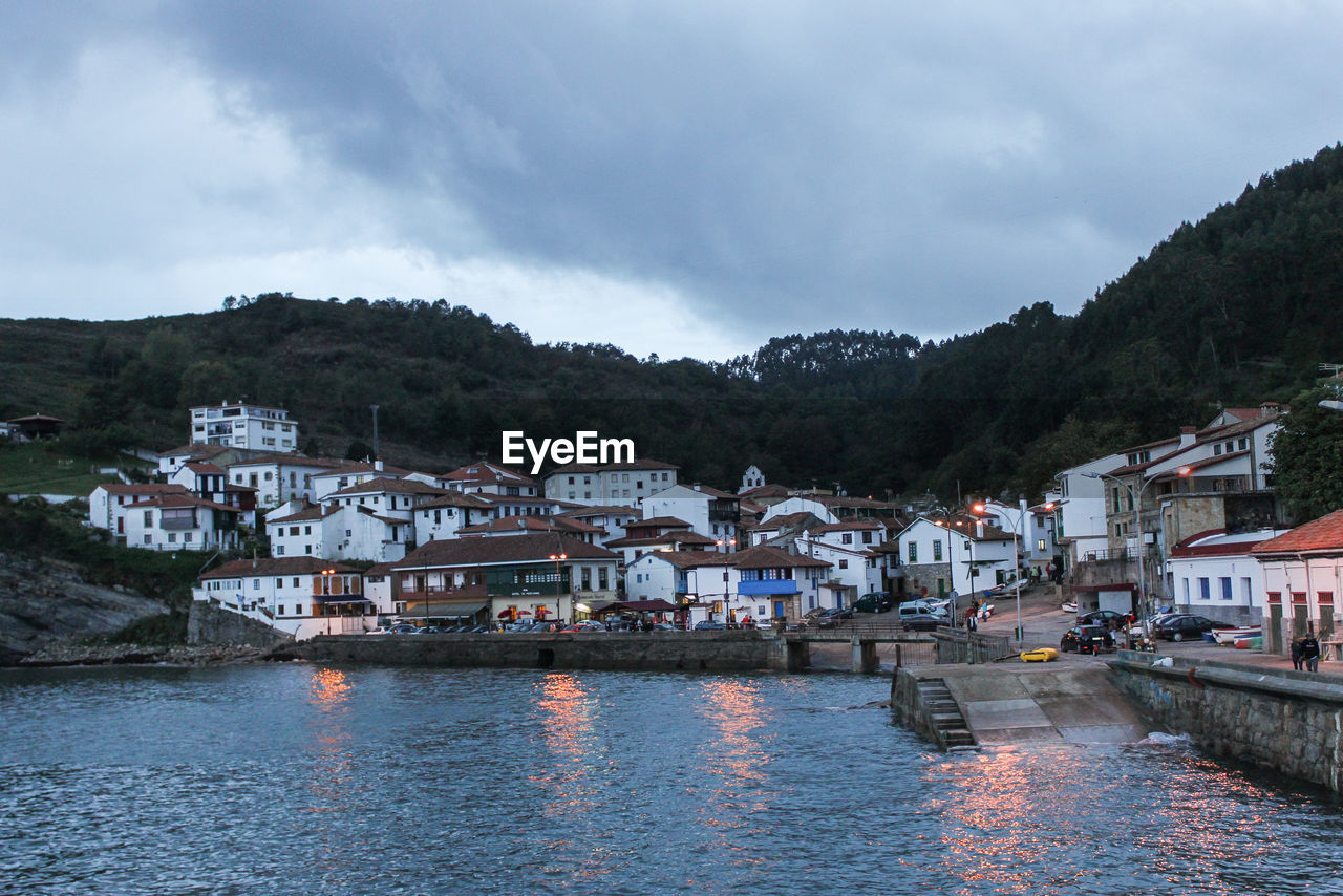 VIEW OF TOWN BY RIVER AGAINST SKY