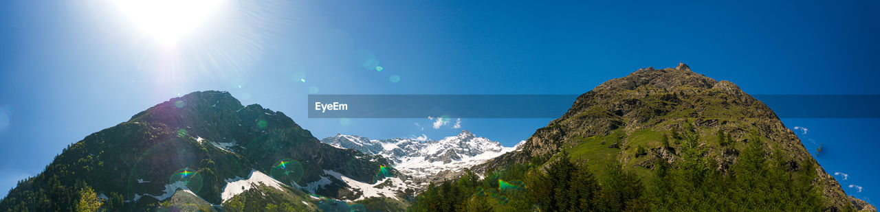 Panoramic view of majestic mountains against blue sky