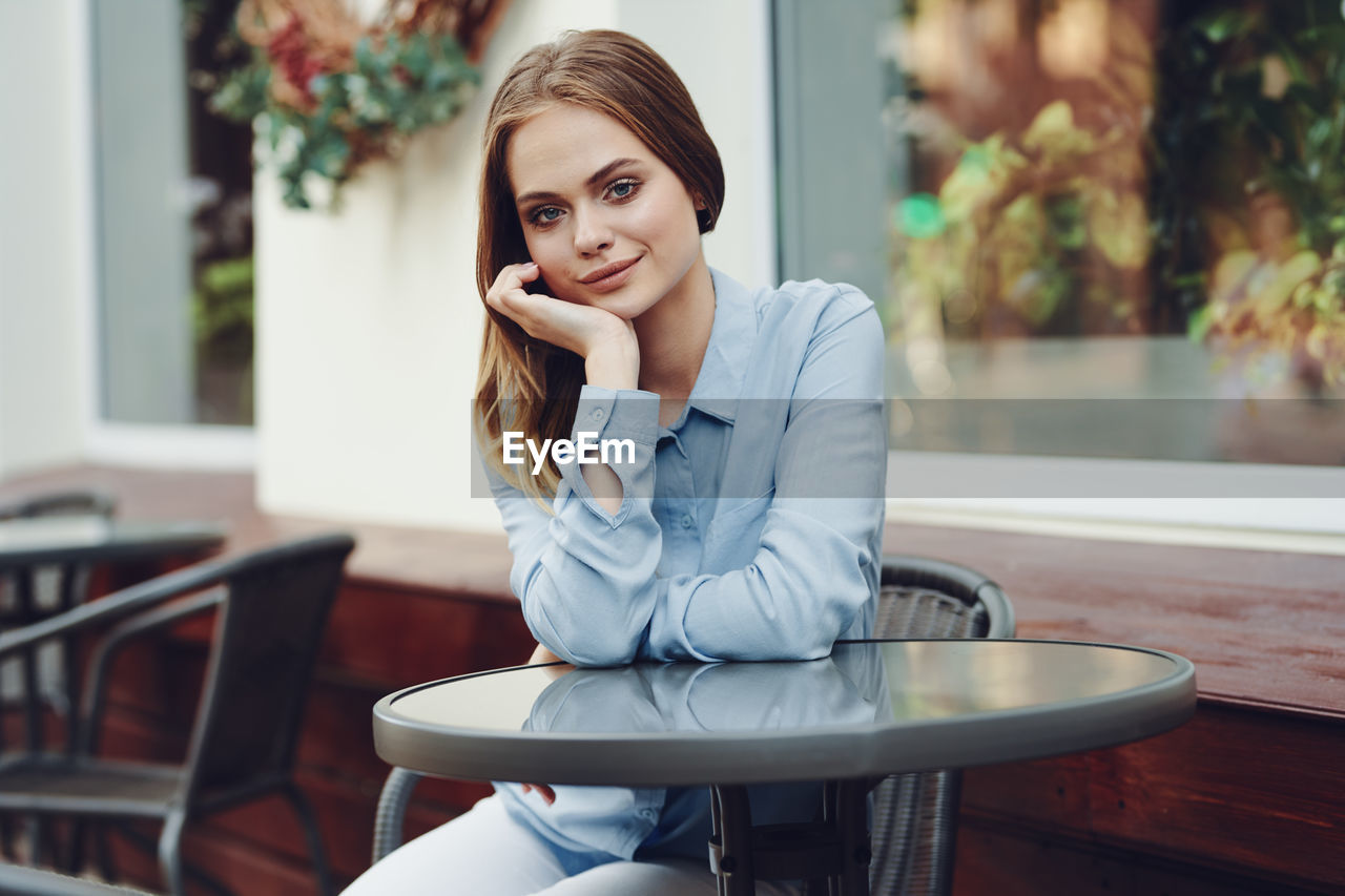 portrait of young woman using mobile phone while sitting in cafe