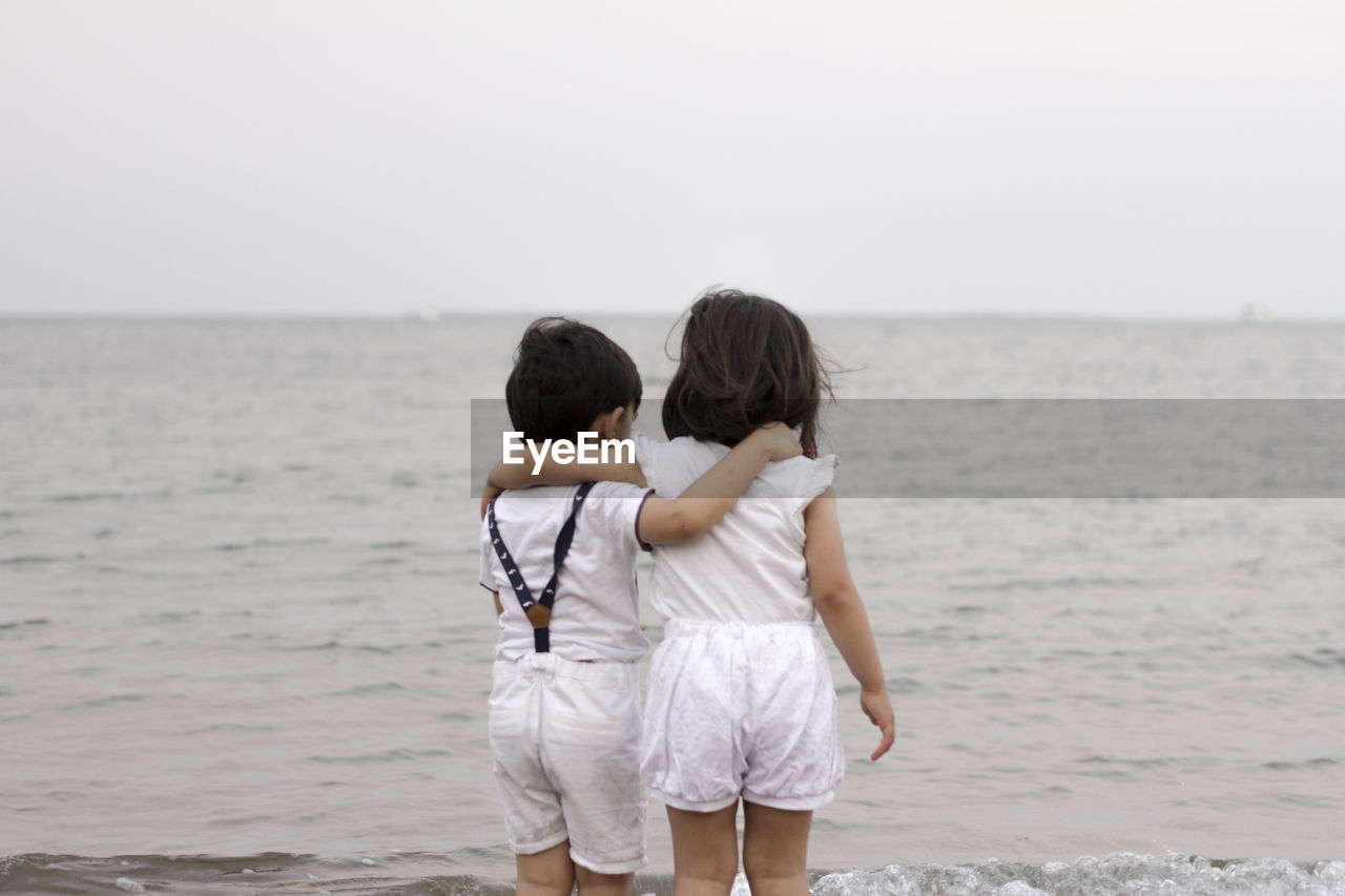 Two kids, one boy and one girl hugging each other at the beach