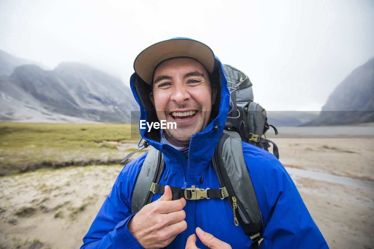 Portrait of happy backpacker with blue rain jacket on.