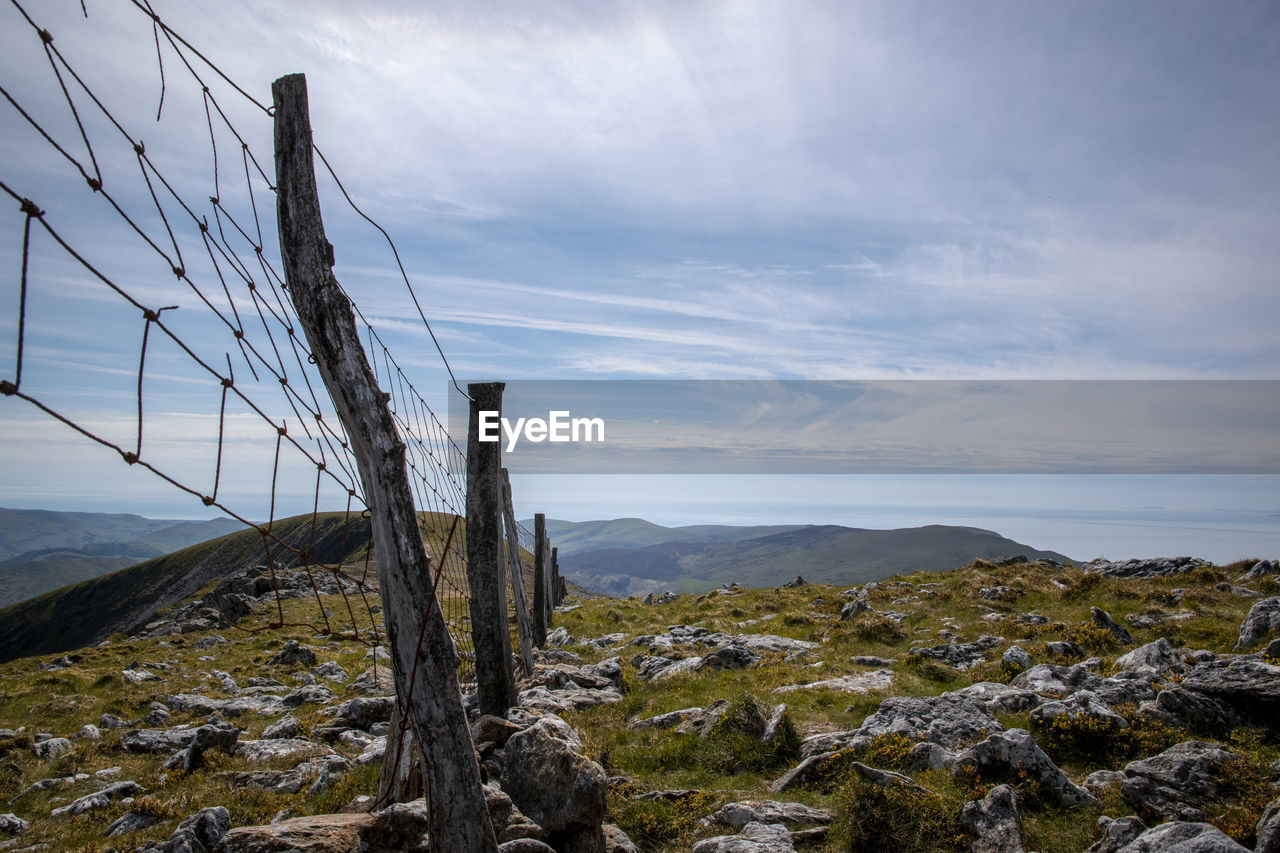 VIEW OF WOODEN POSTS ON LAND AGAINST SKY