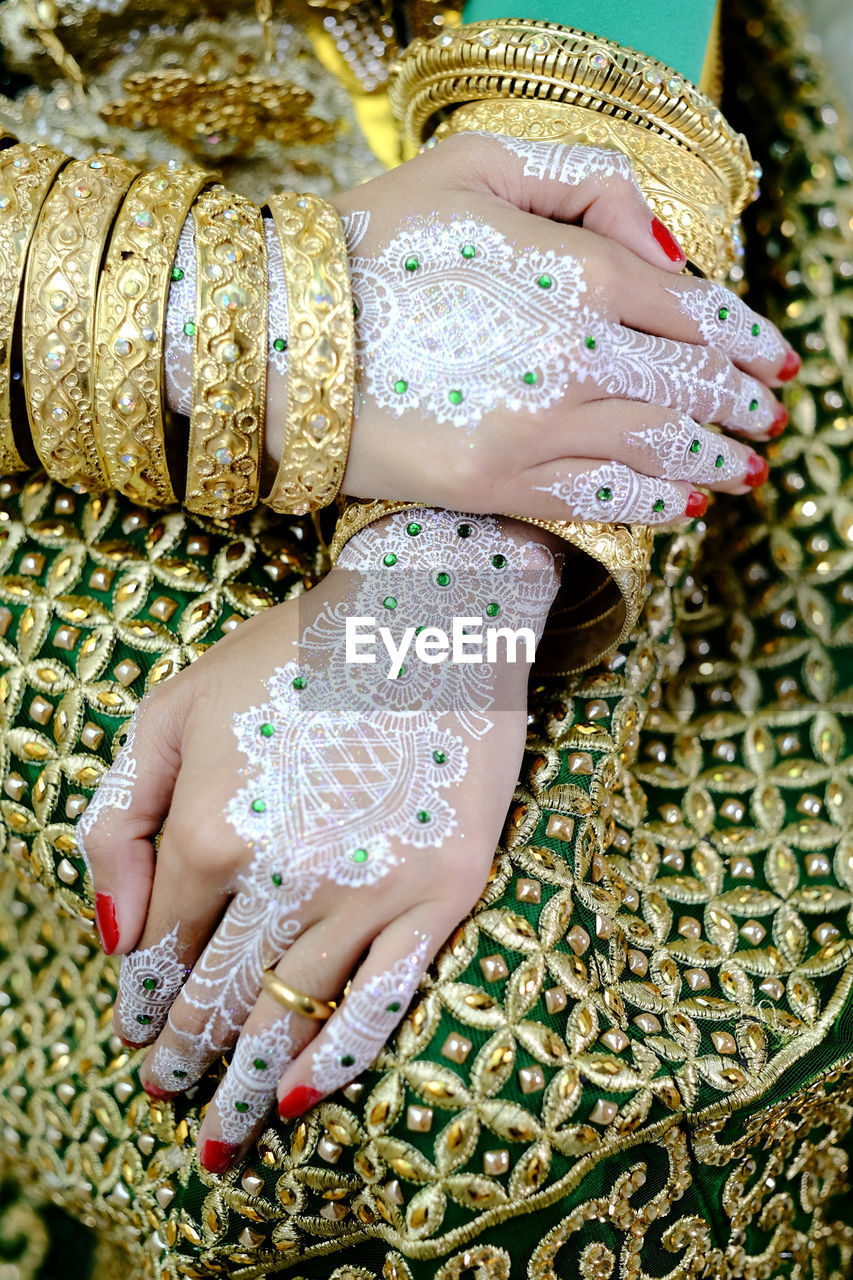 Midsection of woman with heena tattoo on hands