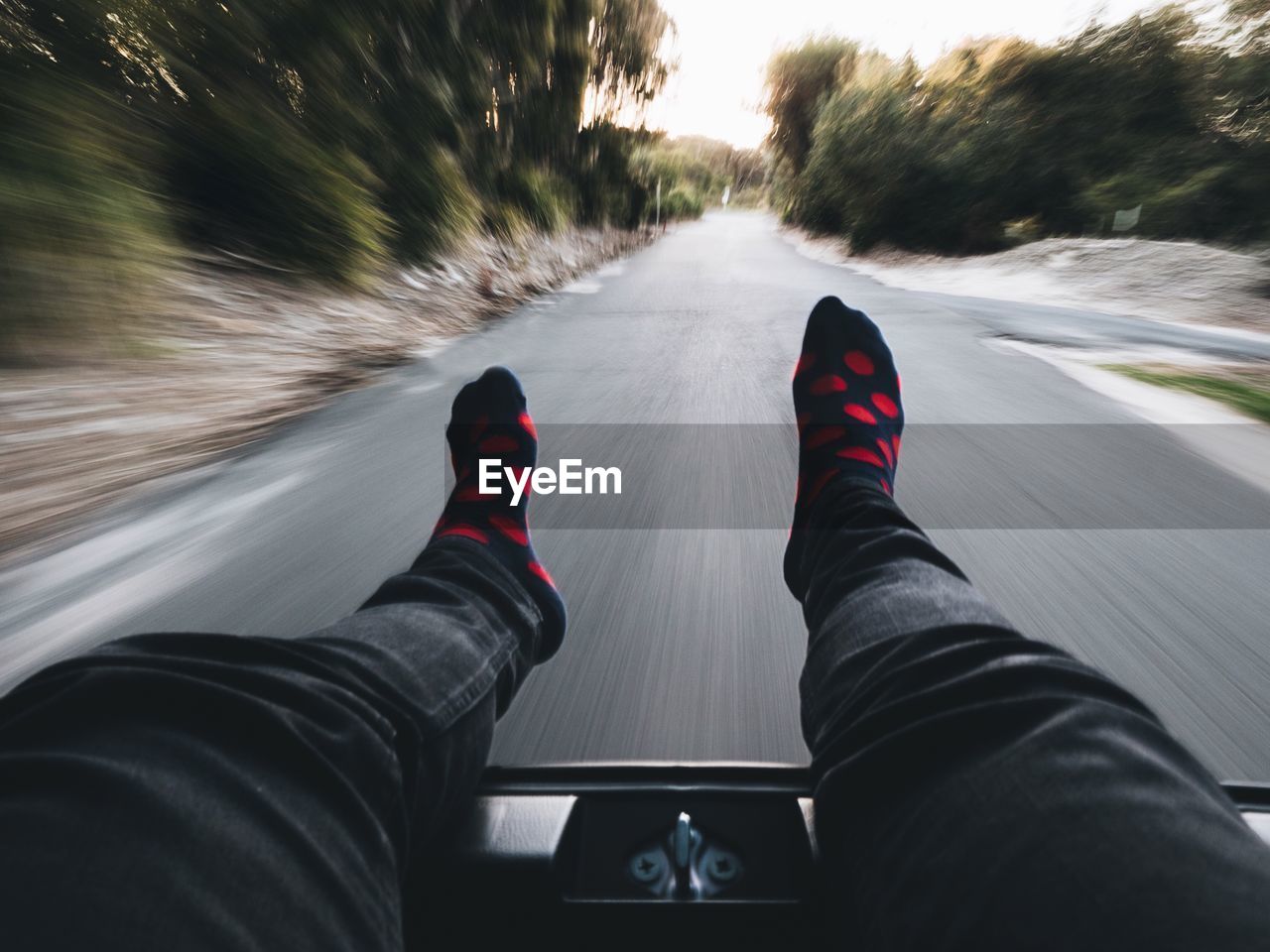 Low section of person relaxing in moving car on road