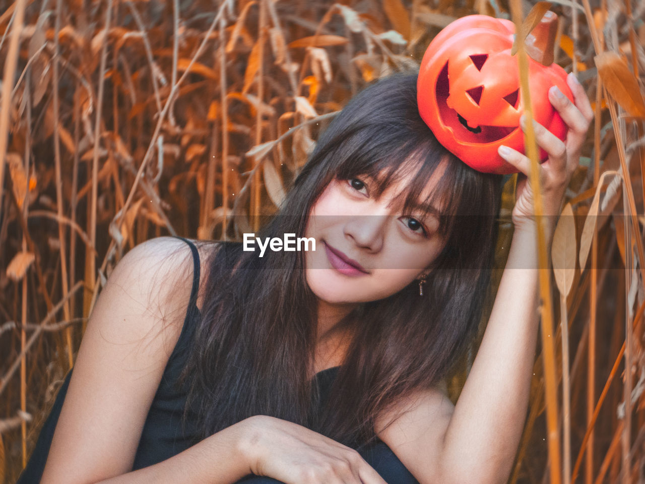Portrait of woman holding jack o lantern amidst plants