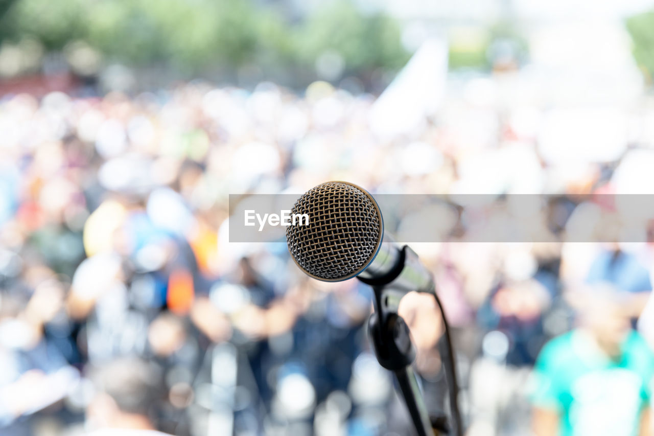 Focus on microphone, blurred group of people at mass protest