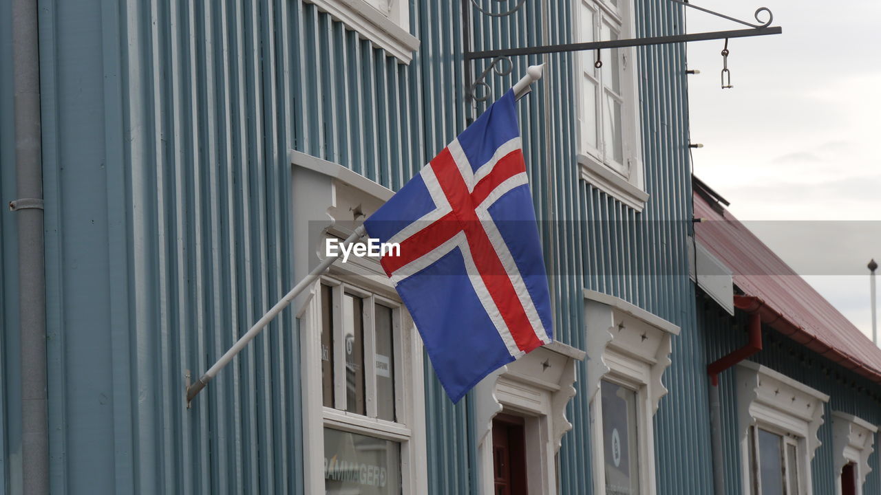 Low angle view of icelandish flag against  wooden blue buildings