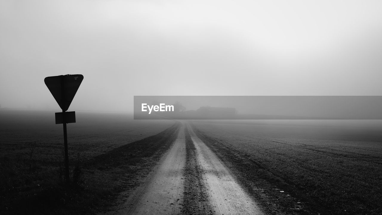 ROAD SIGN ON STREET AGAINST SKY IN FOGGY WEATHER