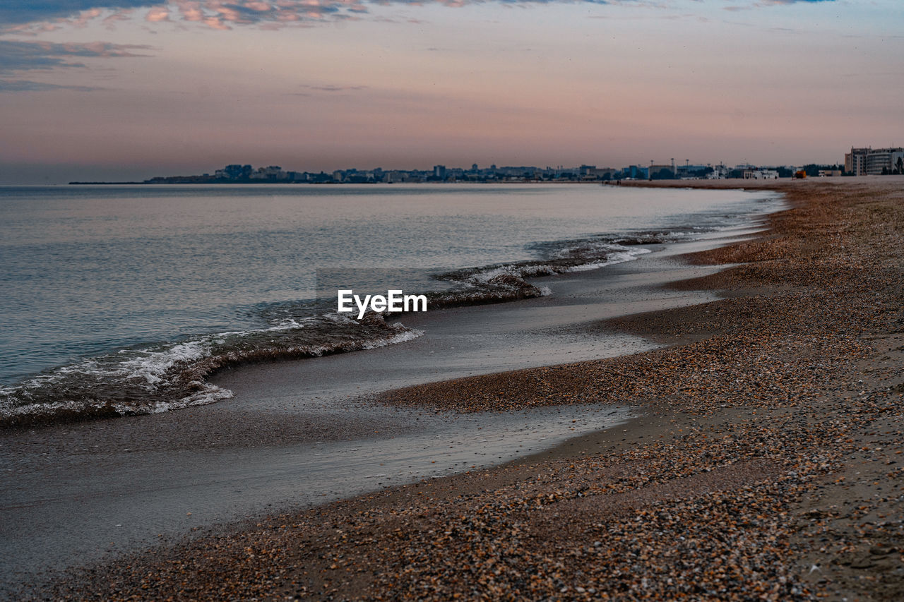 Scenic view of beach and city against sky during sunrise