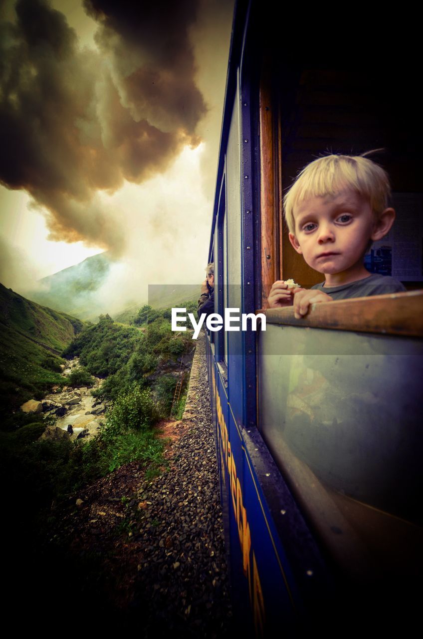 Portrait of boy seen through train window during stormy weather