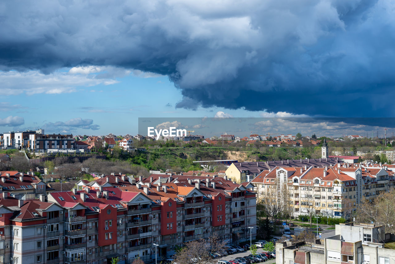 Stormy sky and rainy clouds above a quarter of city residential buildings